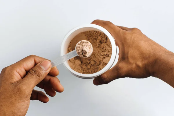 Mãos Segurando Uma Colher Proteína Chocolate Sobre Fundo Branco — Fotografia de Stock