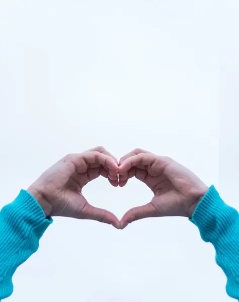 Bir kalp, aziz sevgililer günü ve aşk konsepti yapan iki elin dikey çekimi.
