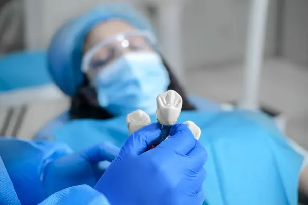 Eldivenli eller diş implantı modelini gösteriyor..