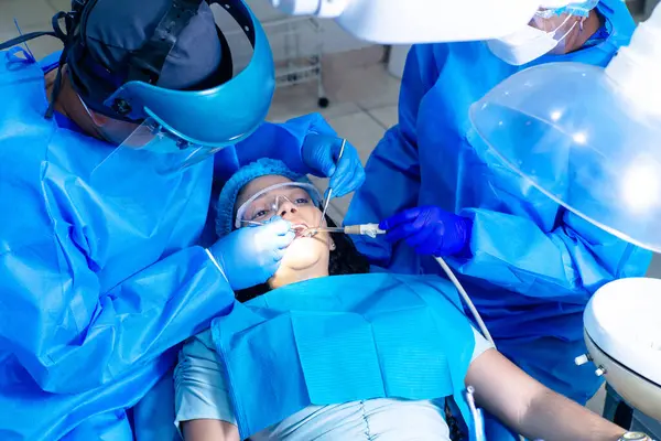 Dişçiler, parantezli bir kadın hastaya endodontik yapıyor..