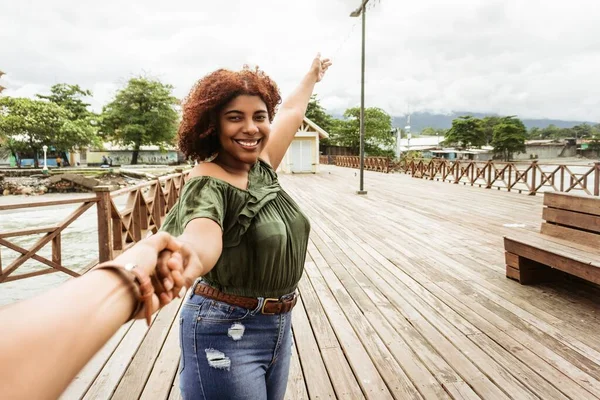 Genç ve mutlu bir kadının yürürken erkek arkadaşının elini tutuşu..