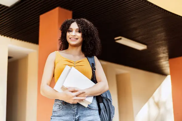 Mutlu Latin Amerikalı öğrenci kitap tutuyor..