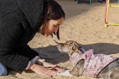 Genç bir kadın dışarıda köpeğiyle yüz yüze geliyor.