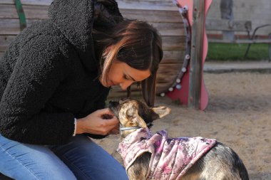 Genç bir kadın dışarıda köpeğiyle yüz yüze geliyor.