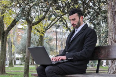 Sokakta bilgisayar kullanan takım elbiseli bir adam.