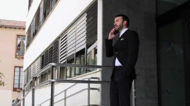 Takım elbiseli adam merdivenlerden inerken telefonda konuşuyor.