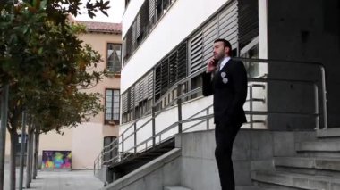 Takım elbiseli adam merdivenlerden inerken telefonda konuşuyor.