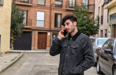 Şirin bir çocuk. Sokakta telefonda konuşan genç beyaz bir adam. Kıvırcık saçlı, yarı vücut, sıradan bir elbise.