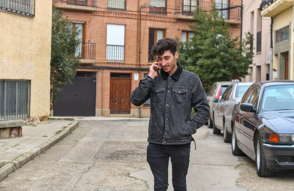 Cute guy just young white guy talking on the phone on the street, curly hair, almost half body, casual dress