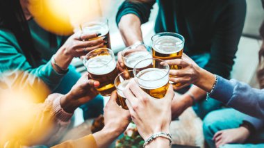 Mutlu arkadaşlar bar masasında mutlu saatler geçirmenin keyfini çıkarıyorlar. Bira bardaklarının yakın plan görüntüsü. Yiyecek ve içecek yaşam tarzı konsepti
