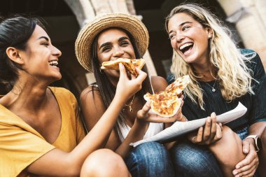 Şehir caddesinde pizza yiyen üç kadın. Mutlu yaşam tarzı ve turizm konsepti