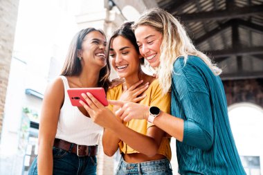 Milenyum kadınları şehir caddesinde cep telefonu kullanıyor. Teknoloji, sosyal, arkadaşlık ve gençlik kavramı