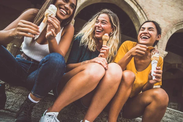 10代の女の子が街中でアイスクリームコーンを食べて笑っています 夏のライフスタイルのコンセプト — ストック写真