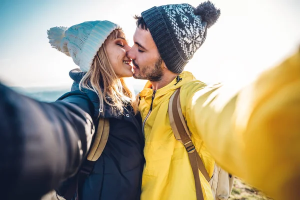 徒步旅行的男女在山顶上自拍 在阳光灿烂的日子里 情侣们在户外亲吻 — 图库照片