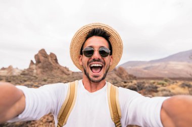 Mutlu yürüyüşçü dağın tepesinde bir selfie çeker - genç adam kendi portresini yapar tatilde yürüyüş yapar - spor seyahat konsepti