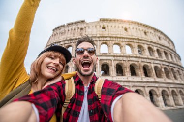 İtalya, Roma 'da Colosseum' u ziyaret eden mutlu bir çift. Genç Arkadaşlar, Avrupa 'yı ziyaret eden Guy ve Kız Kolezyum' da akıllı telefonlarıyla selfie çekiyor. Seyahat etkisindeki teknoloji ve aşk konsepti.