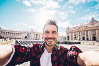 Roma 'nın Vatikan şehrindeki St. Peters Katedrali' nin önünde akıllı telefonlu selfie portresi çeken mutlu beyaz adam Seyahat Etkisi Teknolojisi sosyal medya kavramı