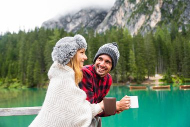 Braies Italya 'daki bir alp gölünü ziyaret eden iki yetişkinin romantik öpücüğü - Sonbahar dağlarında sıcak çikolata içen bir turist - çift, seyahat ve seyahat kavramı