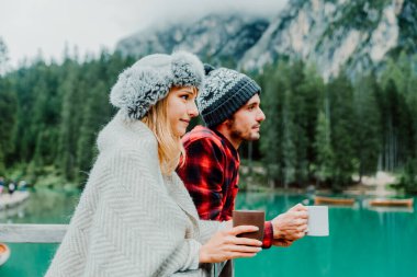 Braies Italya 'daki bir alp gölünü ziyaret eden iki yetişkinin romantik öpücüğü - Sonbahar dağlarında sıcak çikolata içen bir turist - çift, seyahat ve seyahat kavramı