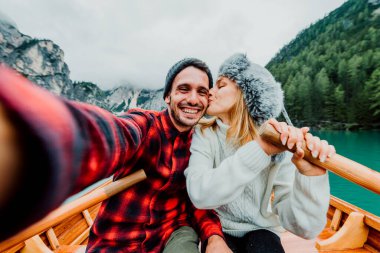Birbirine aşık romantik yetişkinler botla selfie çekiyorlar Braies, İtalya 'daki bir alp gölünü geziyorlar - çift, teknoloji, seyahat ve mutlu yaşam tarzı kavramı - soğuk renkler.