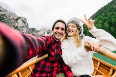 Birbirine aşık romantik yetişkinler botla selfie çekiyorlar Braies, İtalya 'daki bir alp gölünü geziyorlar - çift, teknoloji, seyahat ve mutlu yaşam tarzı kavramı - soğuk renkler.