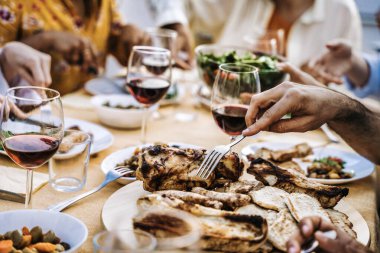 Mutlu bir aile restoranın çatısında akşam yemeği veriyor, bir grup insan et yiyor ve birlikte kırmızı şarap içiyor, yiyecek ve içecek konsepti.