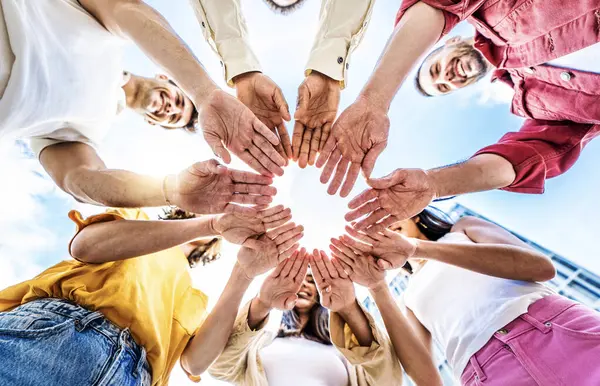 Dışarıda el ele tutuşan bir grup genç kız ve erkeklerin bir arada durduğu takım çalışması konsepti. 