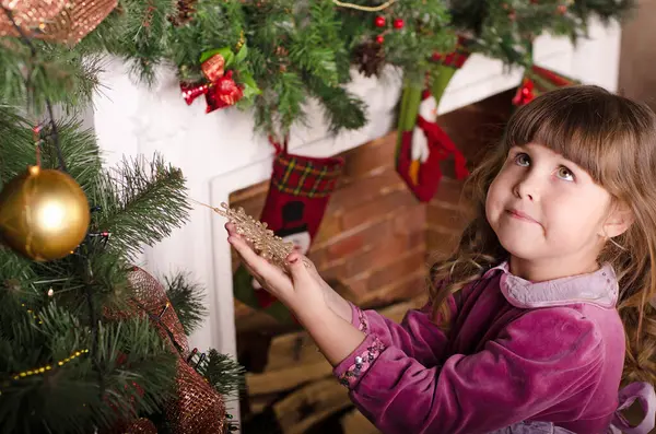 Evde Noel ağacı süsleyen küçük kız.