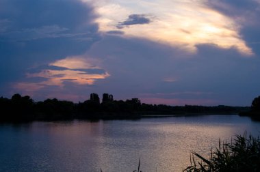 Gölün üzerinde güzel bir gün batımı, suyun üzerinde güzel fırtına bulutları