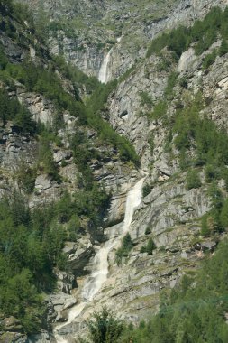 İsviçre 'nin yemyeşil bir vadisinde akan bir şelalenin ham enerjisi dinamik İsviçre manzarasının canlı bir resmini çizer..