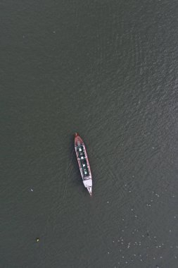 A solitary cargo ship glides through the Douro River, its reflection a faint sketch on the water's surface. This aerial capture of maritime transport in Portugal highlights the tranquil waters and the quiet strength of river navigation. The surroundi