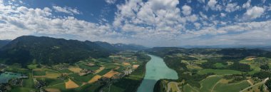 The lush greenery of a river valley unfolds in panoramic splendor in this expansive drone shot, capturing the agricultural beauty of the Slovenian countryside.