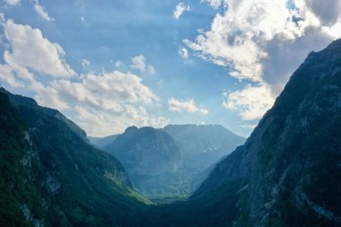 From a high vantage point, a drone reveals the majestic sweep of a mountain range in Austria, with lush forests at its base, encapsulating the grandeur of the natural world.