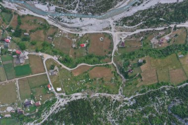 An aerial snapshot of Albania's Shkoder diverse terrain with a winding river slicing through the rural landscape, showcasing the harmony between nature and the cultivated fields.