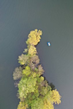 A drone captures the vibrant contrast of a blue kayak against the lush green riverbanks in Minsk, symbolizing tranquility and the joy of nature.