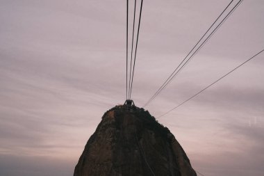 As dusk settles over Rio de Janeiro, the cable car makes its ascent to the summit of Sugarloaf Mountain, offering passengers a breathtaking view of the city's twilight. 