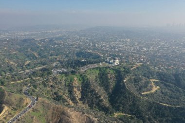 From a bird's eye view, the Griffith Observatory sits perched above Los Angeles, offering a window to the stars against the backdrop of the sprawling city, captured by drone photography.