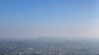 The vastness of Los Angeles unfolds under the hazy sunlight, revealing the city's dense neighborhoods with the drone's all-seeing eye, highlighting the urban sprawl in the clarity of day.
