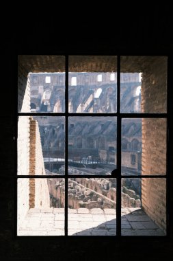 Gaze through an antique window framing the Colosseum, a unique perspective that merges Rome's ancient glory with the intimacy of its storied past. This view offers a moment of contemplation for the empire's profound legacy.