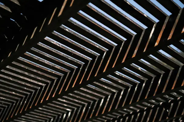 This image from Brazil features the abstract pattern created by metal bars, forming a striking visual texture that plays with perspective and depth. The interlocking lines and the play of light and shadow produce a hypnotic effect, showcasing the bea
