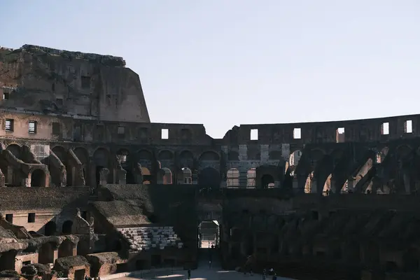 The Colosseum's arches cast shadows that play across its weathered stones, creating a dramatic interplay of light and darkness. This ancient amphitheater, a masterpiece of Roman engineering, continues to awe visitors in the heart of Rome.