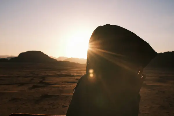 As the sun sets over the Jordanian desert, silhouetted figures add a mysterious dimension to the scene, capturing the awe-inspiring moments of day\'s end in the vast and timeless desert landscapes.