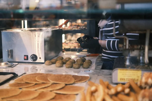 A glimpse into the sweet life of Amsterdam, this image invites the senses to savor the preparation of traditional Dutch stroopwafels. The warm, golden syrup filling spread on the freshly baked wafers is a treat for the eyes, embodying the comfort and