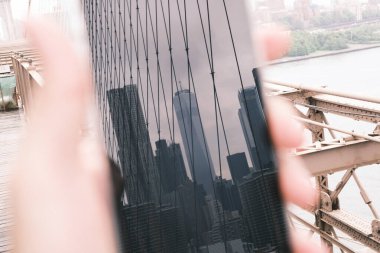 A blurred vision of the New York City skyline from the Brooklyn Bridge, presenting a dreamlike view that merges the bustling city life with the calmness of the surrounding waters.