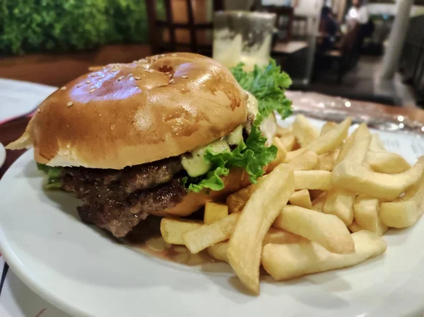 Marul ve mayonezli hamburger, iştah açıcı ve sulu, yanında da kızarmış patates.