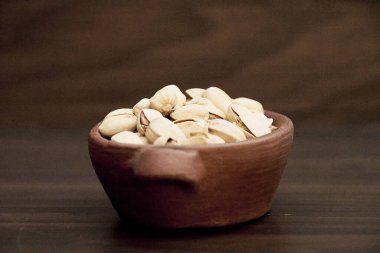 Kahverengi bir masada el yapımı seramik bir akvaryumda lezzetli kurutulmuş fıstık.