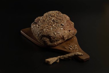 Koyu bir zemin üzerinde çoklu tahıl tohumlarıyla evde yapılan ve pişirilen zanaatkar ekmek, aileyle birlikte yemek için sağlıklı bir ürün..