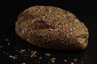 Koyu bir zemin üzerinde çoklu tahıl tohumlarıyla evde yapılan ve pişirilen zanaatkar ekmek, aileyle birlikte yemek için sağlıklı bir ürün..