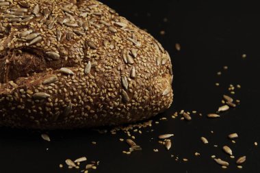 Koyu bir zemin üzerinde çoklu tahıl tohumlarıyla evde yapılan ve pişirilen zanaatkar ekmek, aileyle birlikte yemek için sağlıklı bir ürün..