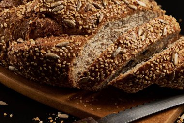 Koyu bir zemin üzerinde çoklu tahıl tohumlarıyla evde yapılan ve pişirilen zanaatkar ekmek, aileyle birlikte yemek için sağlıklı bir ürün..